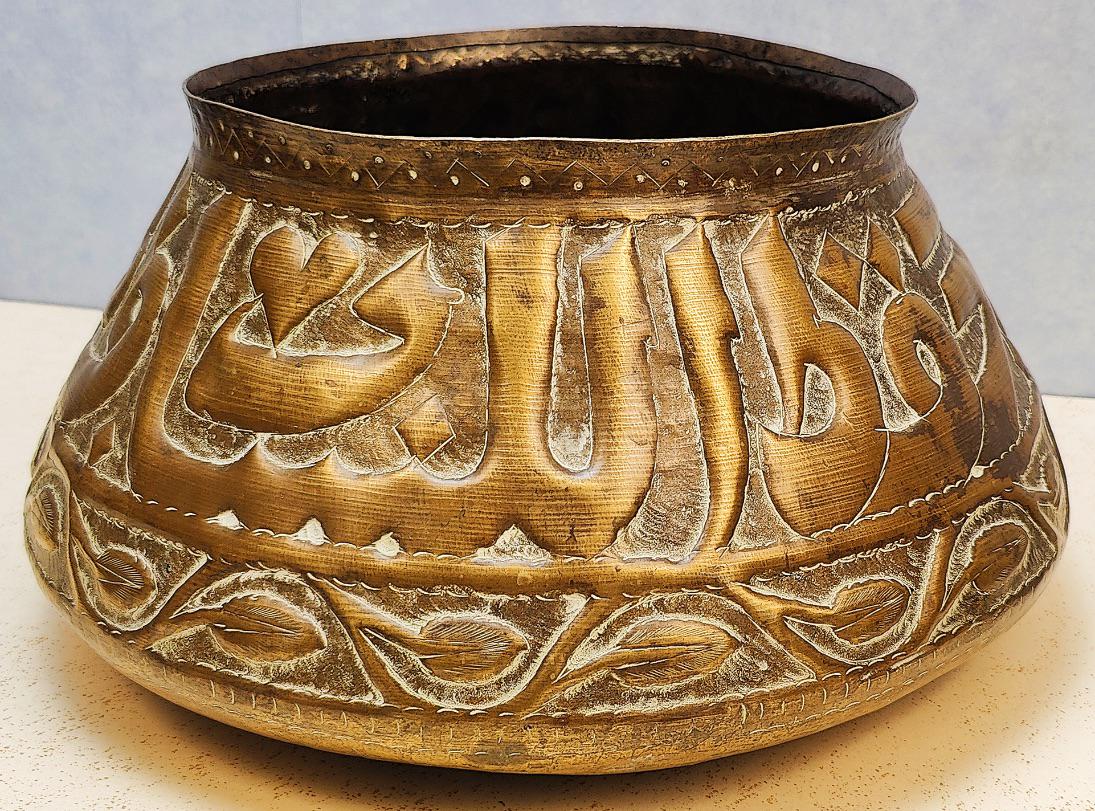 An early 20th century brass bowl, embossed calligraphic decor, probably Syrian or Egyptian, D.31cm: An early 20th century brass bowl, embossed calligraphic decor, probably Syrian or Egyptian, D.31cm