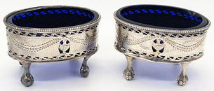 A pair of George III silver salts, pierced bodies, raised on four claw and ball feet, monogrammed,