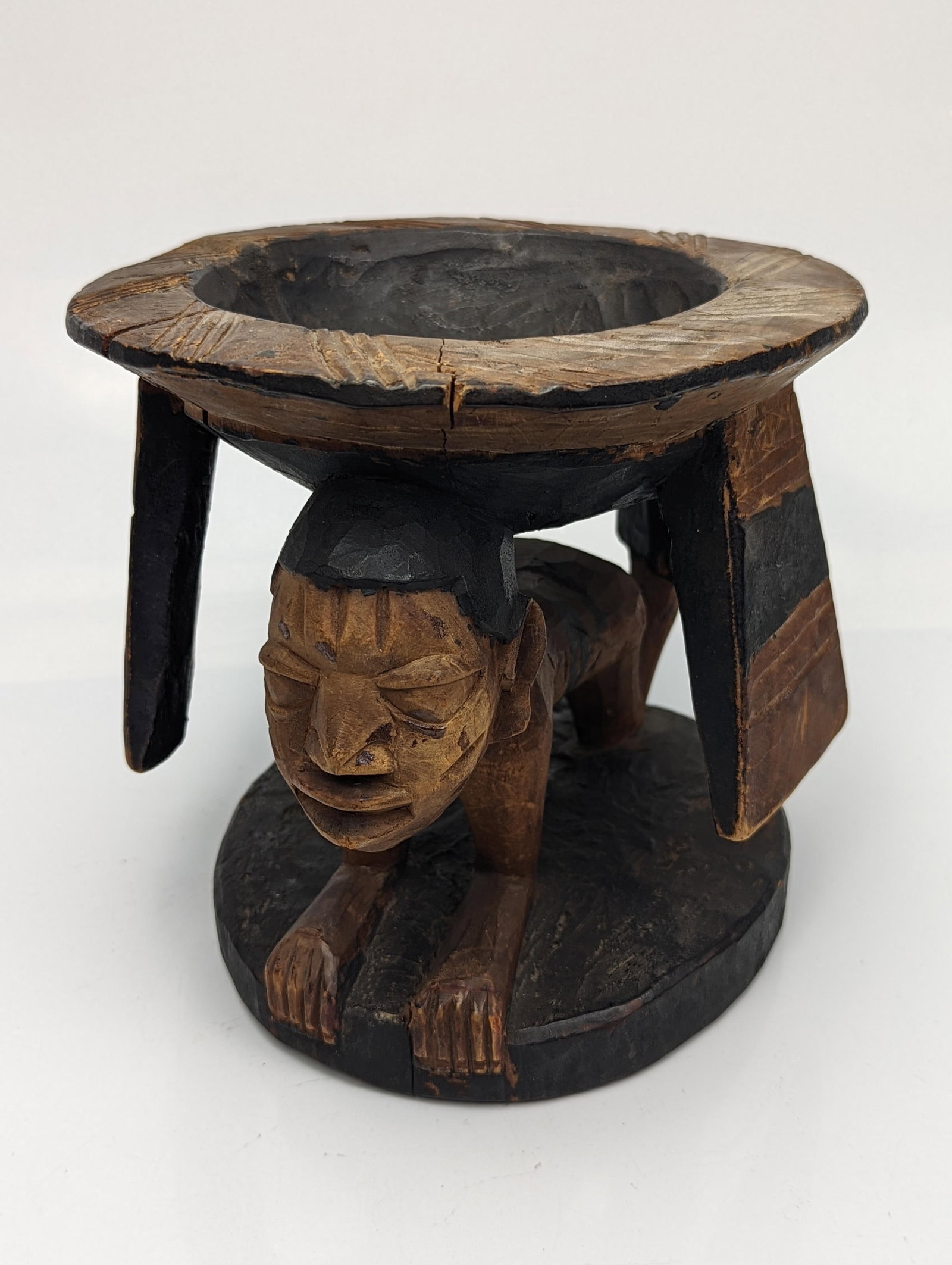 A Nigerian African tribal wooden carved Yoruba Division bowl supported by a nude crawling figure,: A Nigerian African tribal wooden carved Yoruba Division bowl supported by a nude crawling figure, H.16.5cm