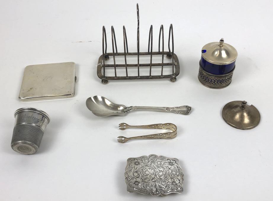 Group of sterling and English silver articles: Approximately 14 ounces Comprising, toast rack, cigarette case, belt buckle, thimble shot glass, sugar thongs, spoon and mustard pot with two lids