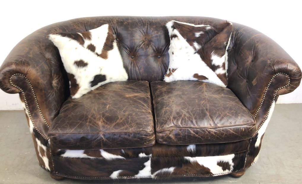 A Leather and Cowhide Buttonback Settee Manufactured by: A Leather and Cowhide Buttonback Settee Manufactured by King Ranch. 35" h x 67" w x 38"w Condition, some minor scratches, 1 minor leather defect hole