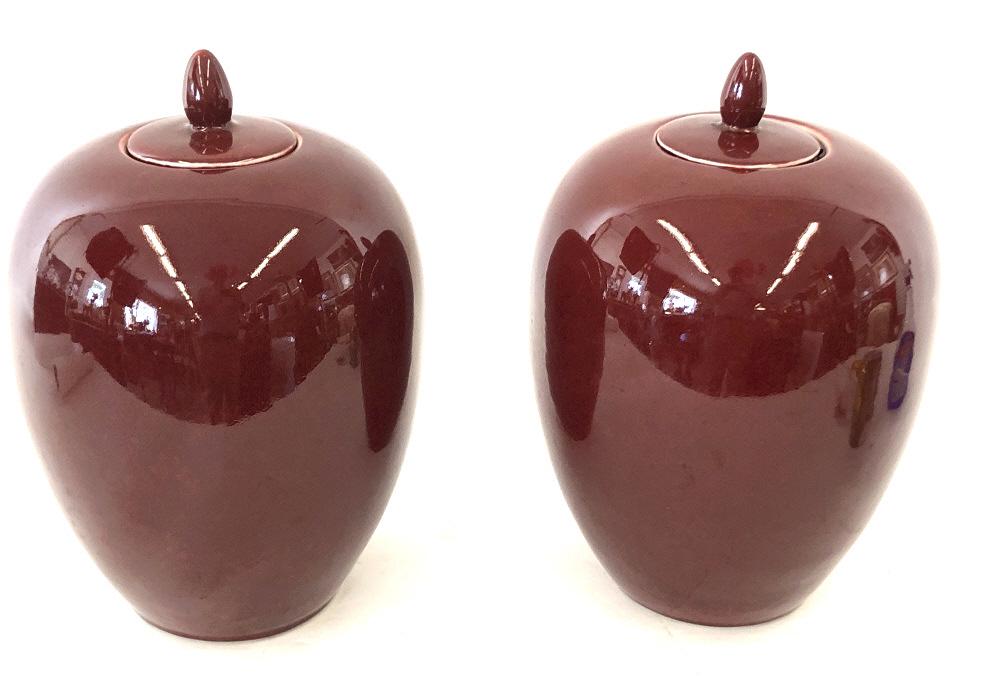 A Pair of Sang de Boeuf Porcelain Ginger Jars Ox Blood. 14" h x 10" diameter. Condition, one jar is: Ox Blood. 14" h x 10" diameter. Condition, one jar is chipped on rim, old repair to one finial