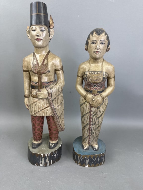 Pair of Carved Wood Indonesian Dignitaries: Pair of Carved Wood Indonesian Dignitaries. Tallest is 19 1/2" h x 5"w x 4 3/4"d. Condition, broken ear, missing a piece from the headwear, cracks, scratches, scuffs