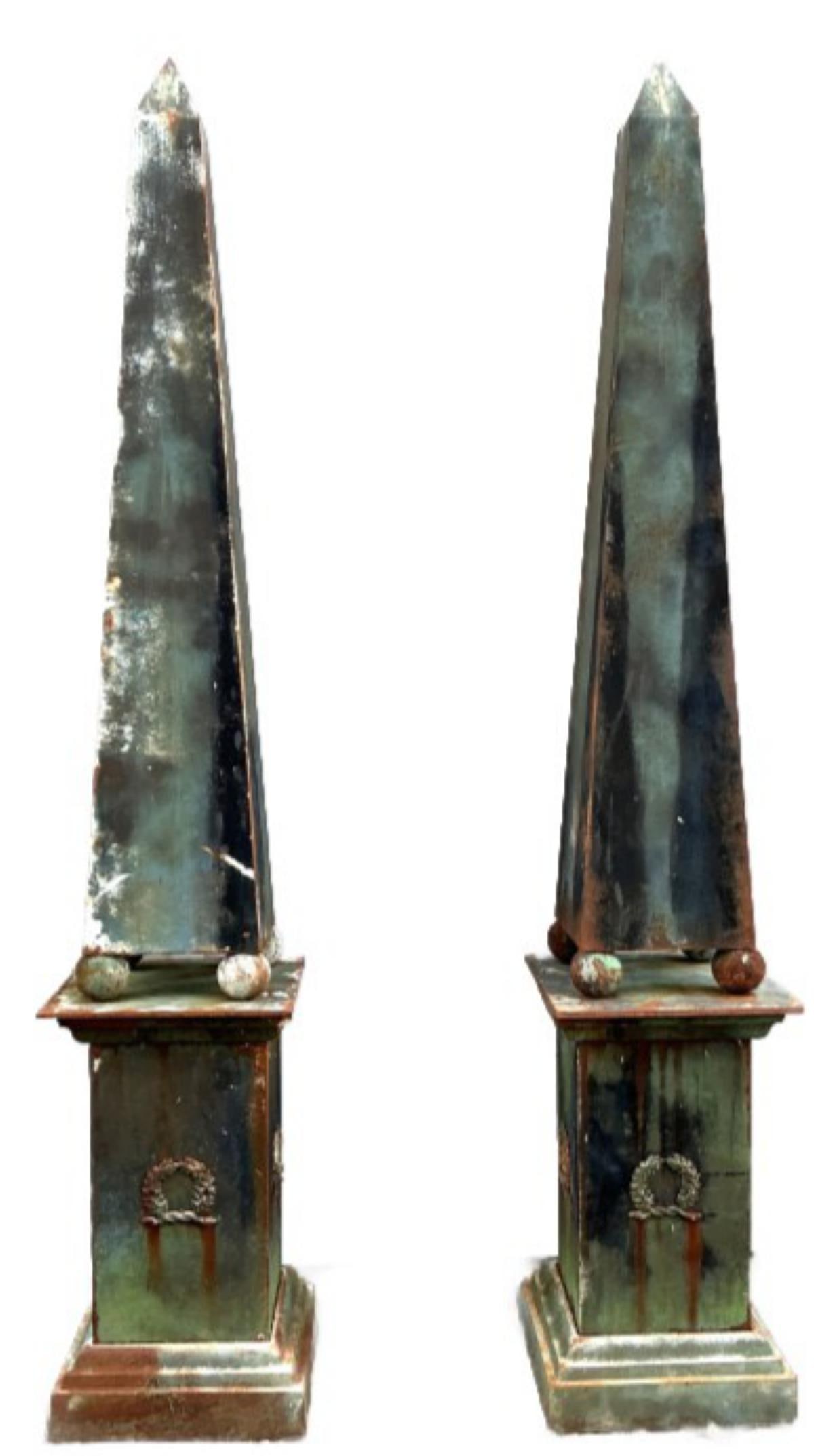 Pair of Obelisks on Cast Iron Pedestals: Pair of metal obelisks on cast iron pedestals. Measure 100"h x 18"w x 18"d. Condition: Some rust, needs painting.