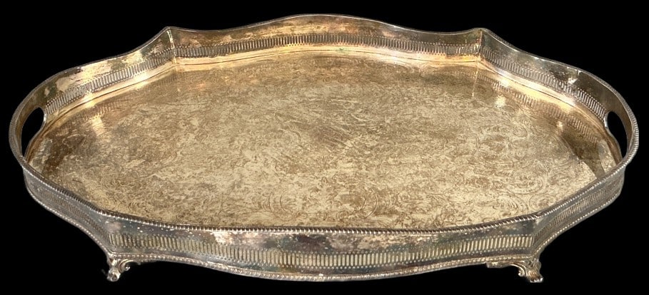 English Silver Plated Serving Tray: English silver plated serving tray. Footed base with pierced gallery rim and chased scroll center. Measures 3"h x 24"w x 16.5"d. Condition: Needs polishing, some scratches.