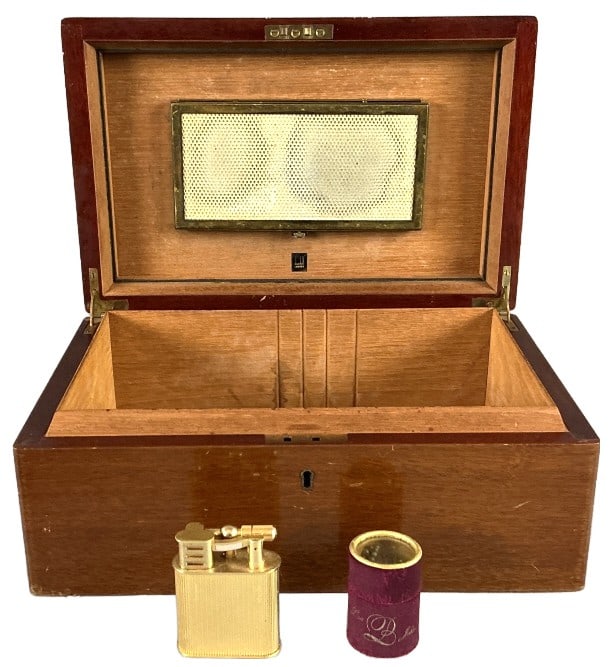 Dunhill Humidor, Table Lighter & Match Box: Grouping of tobacciana. Dunhill mahogany and cedar humidor. Retro brand gold tone table lighter. Lisa B John match box. Humidor measures 5.5"h x 14"w x 9"d. Condition: Surface wear to all pieces. Scra