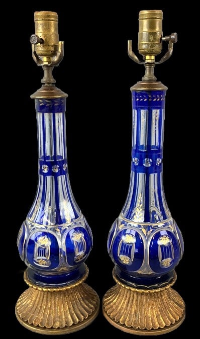 Pair of Bohemian Style Cobalt Cut Glass Lamps: Pair of Bohemian style cobalt blue to clear cut glass lamps with hand painted gilt. Measure 18"h x 5"dia. Condition: Untested. Some scratches.