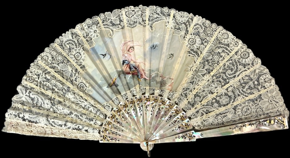 19th Century Mother of Pearl Painted Lace Fan: Late 19th Century folding fan with mother of pearl frame and white lace. Hand painted gouache classical vignette. Measures 24"w. Condition: Some separation of lace to frame, yellowing.