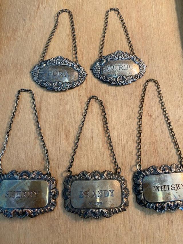 5 Sterling liquor bottle tags: 5 Sterling liquor bottle tags. Rectangle tags measure 2.25 x 1.50 and is marked FHV and Co and another undecipherable mark. Oval tags measure 2.25 x 1.50 and are marked B and Co with an additional und