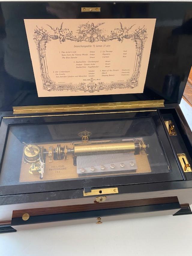 Reuge Cylinder Music Box Swiss: Reuge Cylinder music box. Music box with 5 interchangeable cylinders. Made in Switzerland. Rosewood chest with Brazilian tulipwood inlay. 72 tooth comb plays 15 songs. Includes an informational bookle