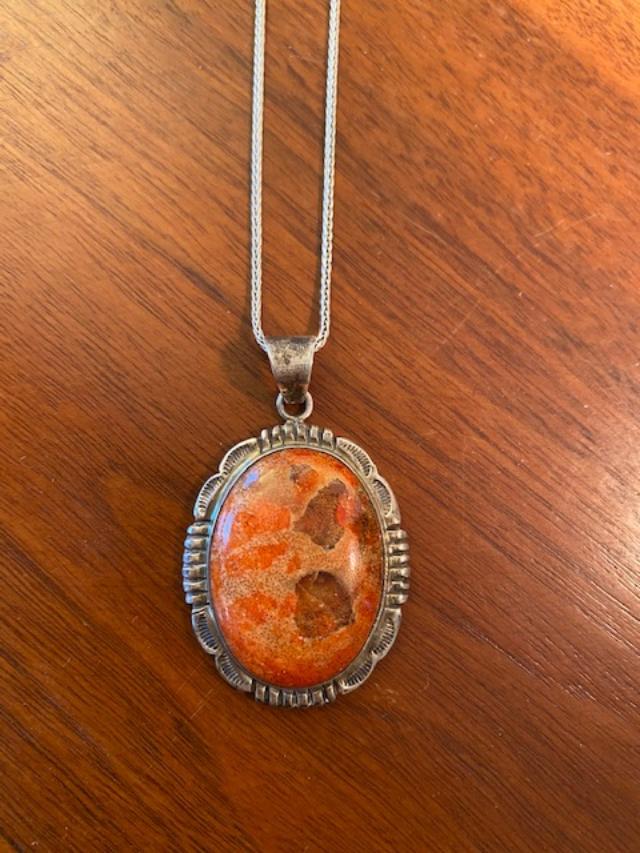Signed Native American Sterling and Stone Pendant: Native American stamped sterling and stone pendant and chain. Natural stone is a orange and red color. Signed "LO." Chain measures 18 inches. Pendant measures 2"X 1". FREE DOMESTIC SHIPPING.