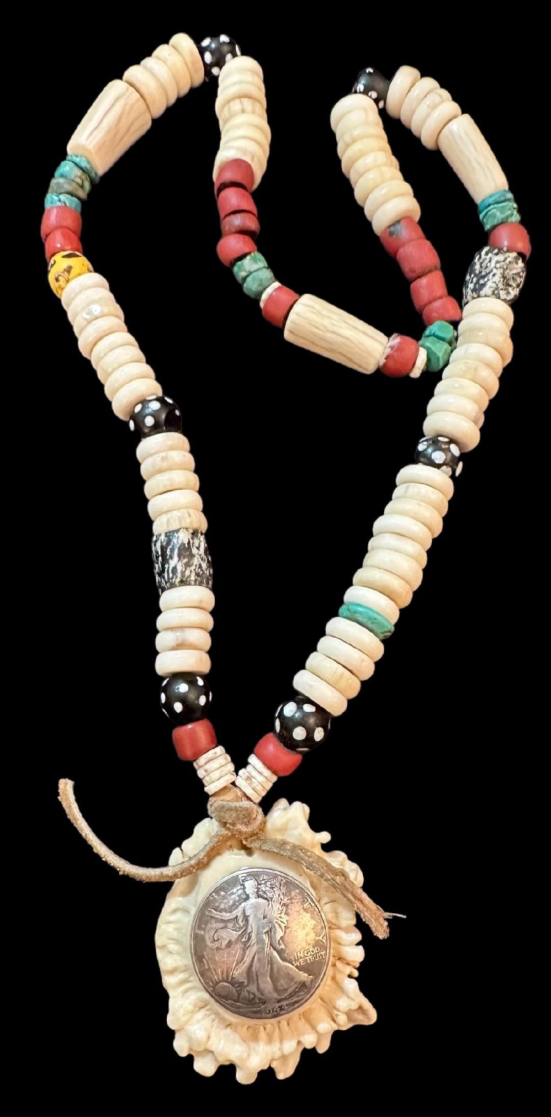 Vintage Native American Santo Domingo Necklace with Walking Liberty Half Dollar Antler Pendant: Vintage Native American, Santo Domingo necklace. Features a 1944 Walking Liberty half dollar pendant. With bone, turquoise and bead spacers. Pendant attached to string necklace with leather. Pendant m