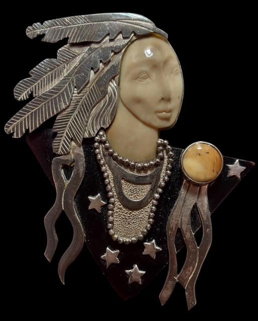 Hand Carved Sterling and Mammoth Bone Brooch Zealandia: Hand carved sterling and mammoth bone brooch. Carved Native American face with glass accents. Copyright Zealandia. Marked .925. Measures 2.75" x 2.25". For in-house shipping, select "bidder arranged".
