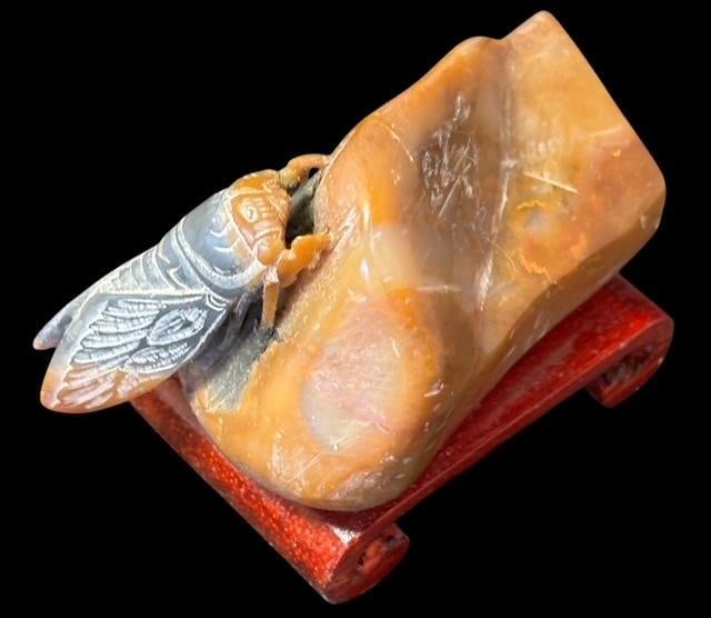 Hand Carved Stone Chinese Cicada Figural on Wood Stand: Hand Carved Chinese stone cicada on a wood stand. Measures 3" long by 2.5" high.