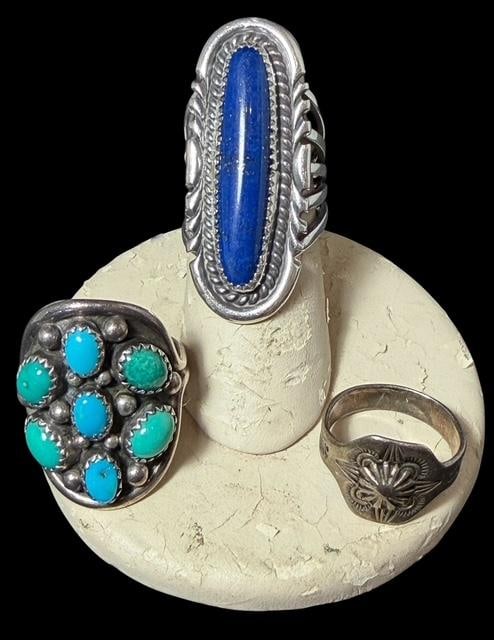 Lot of Three Native American Sterling and Stone Rings: Lot of three Native American sterling and stone rings. 1) Navajo with 7 turquoise stones. Size 9. Has been sized and has crack at rear section. 2) Navajo signed B. Large oval lapis stone in sterling (