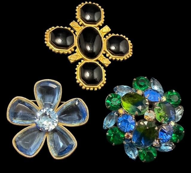 Lot of Three Antique Rhinestone Brooches Kramer, Capri and Karl Lagerfeld: Lot of three costume jewelry brooches. 1) Signed Kramer. Measures 2" with blueish/green multi stone design. 2) Signed Capri. Measures 2" with pale blue glass floral design. 3) Signed KL (Karl Lagerfel