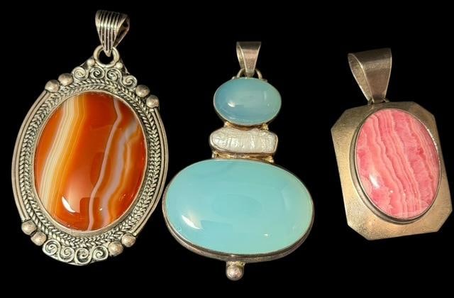 Lot of Three Sterling and Stone Pendants: Lot of three sterling and stone pendants. 1) Agate oval stone. Measures 1.5" x 2.5". 2) Chalcedony stone with faux pearl. Measures 1.5" x 2.5". 3) Pink rhodochrosite stone. Measures 1" x 2". Total wei