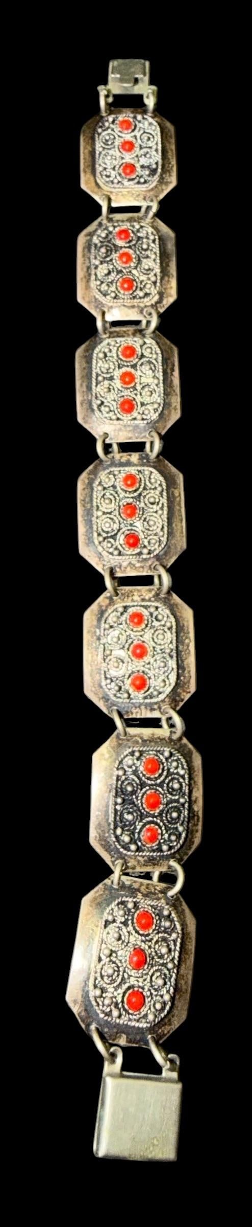 Isralian Sterling and Coral Bracelet: Sterling and red coral bracelet. Marked Jerusalem Israel and sterling. Measures 7" with clasp. Three red stones in each of the seven sections. Total weight 20g.