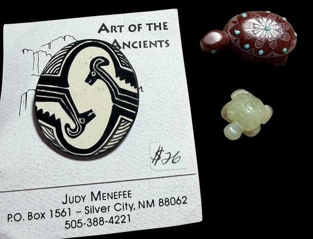 Lot of Three Native American Turtle Fetish, Zuni Pipe Stone Turtle & Membres Style Pin: Lot of three carved Native American items. 1) carved turtle fetish. Measures 1". 2) Zuni pipe stone by Daphne Neha. Measures 1.5". 3) Mimbres type pin. Measures 1.5" x 1.5".