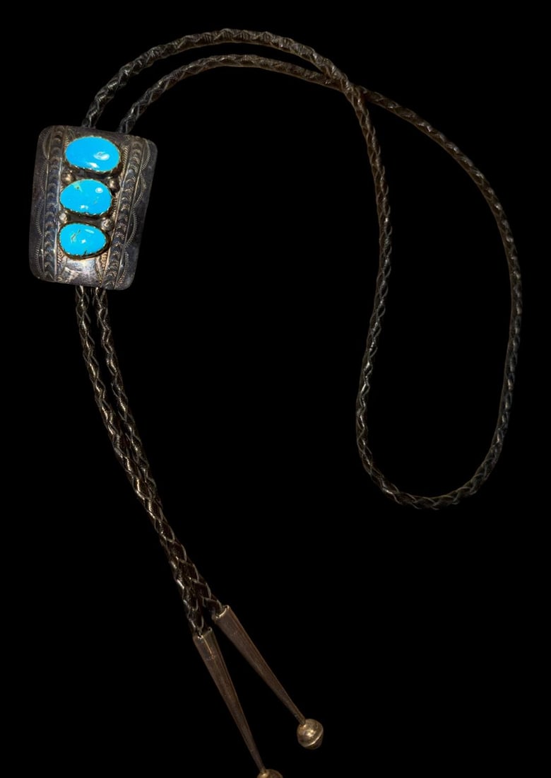 Navajo Sterling and Turquoise Navajo Bolo Tie: Sterling bolo tie with sterling tips and three turquoise stones. Marked sterling and signed S. Bolo Measures 1.5" x 2". Bolo length is 38".