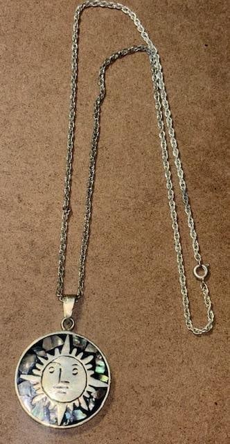 Mexican Mayan Sun Pendant Necklace Abalone: Mexican Mayan sun face pendant on a 24" silvertone chain. Pendant measured .925. Pendant inlaid with silver and abalone. Measures 1.5" across.