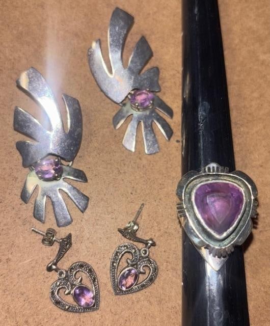 Lot of Three Amethyst Jewery Earrings and Ring: Lot of three amethyst jewelry pieces. Two pairs of earrings and one ring. 1) Heart shaped amethyst and has marcasite side pieces. Measures .5" x 1". 2) Earrings measure .75" x 1.75" and dated 1987. 3)