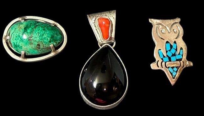 Lot of Three Sterling Pins and Pendant: Lot of one sterling pendant and two brooches. 1) Oval shaped pin with polished malachite center stone. Tested sterling. Measures 1.25" x 1". 2) Oval pendant with onyx center stone and coral accent. Ma