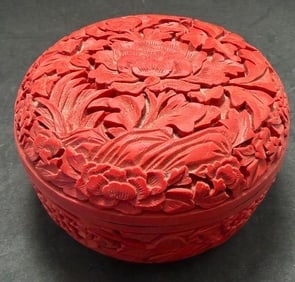 Chinese Red Cinnabar Round Trinket Box: Chinese red cinnabar carved floral round trinket box. Black lacquer interior. Measures 2.75" high by 4.25" across.