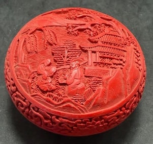 Chinese Red Cinnabar Round Trinket Box: Chinese red cinnabar carved floral round trinket box. Black lacquer interior. Measures 2.25" high by 4.50" across.