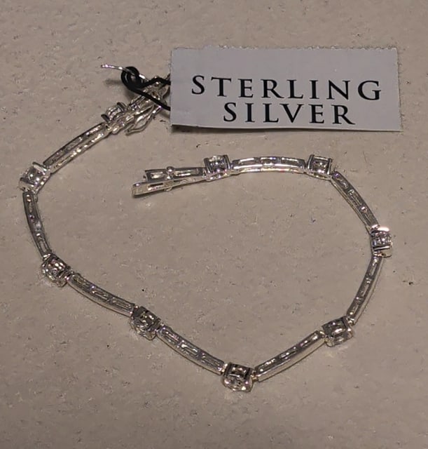 Sterling and Cubic Zirconia Tennis Bracelet: Sterling and cubic zirconia tennis bracelet. Tag still attached. Measures 7" around by 1/8" wide. Weighs 7g.