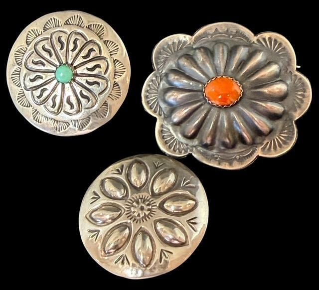 Lot of Three Native American Navajo Sterling and Stone Brooches Signed: Lot of three Native American Navajo sterling and stone pins. 1) Marked sterling and signed Rog Daye. Coral center stone in a fluted concho shape. Measures 1.25" x 1". 2) Marked sterling and signed SN.