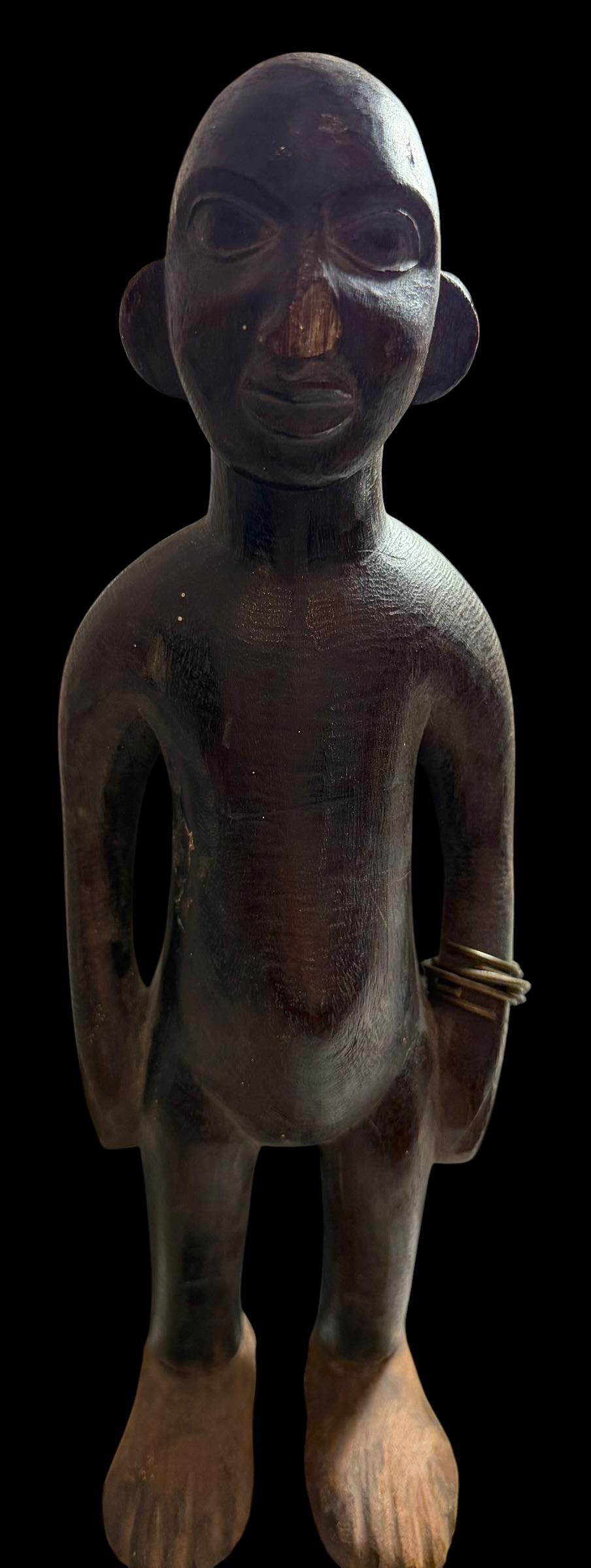 African Hand Carved Tribal Figure: African hand carved tribal male figure. Has a coiled copper bracelet on one arm. Measures 12.5" high by 4.5" wide.