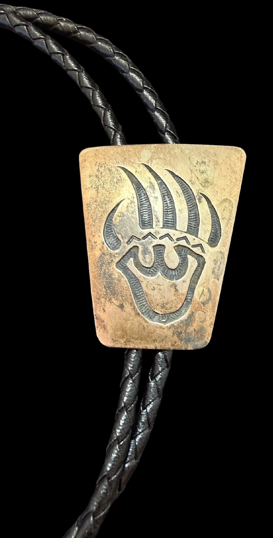 Native American Navajo Sterling Bolo Tie: Native American Navajo sterling (tested) bear paw imprint bolo tie with sterling tips. Cord measures 36". Round bolo measures 1.25" x 1.75". No artisan hallmark.
