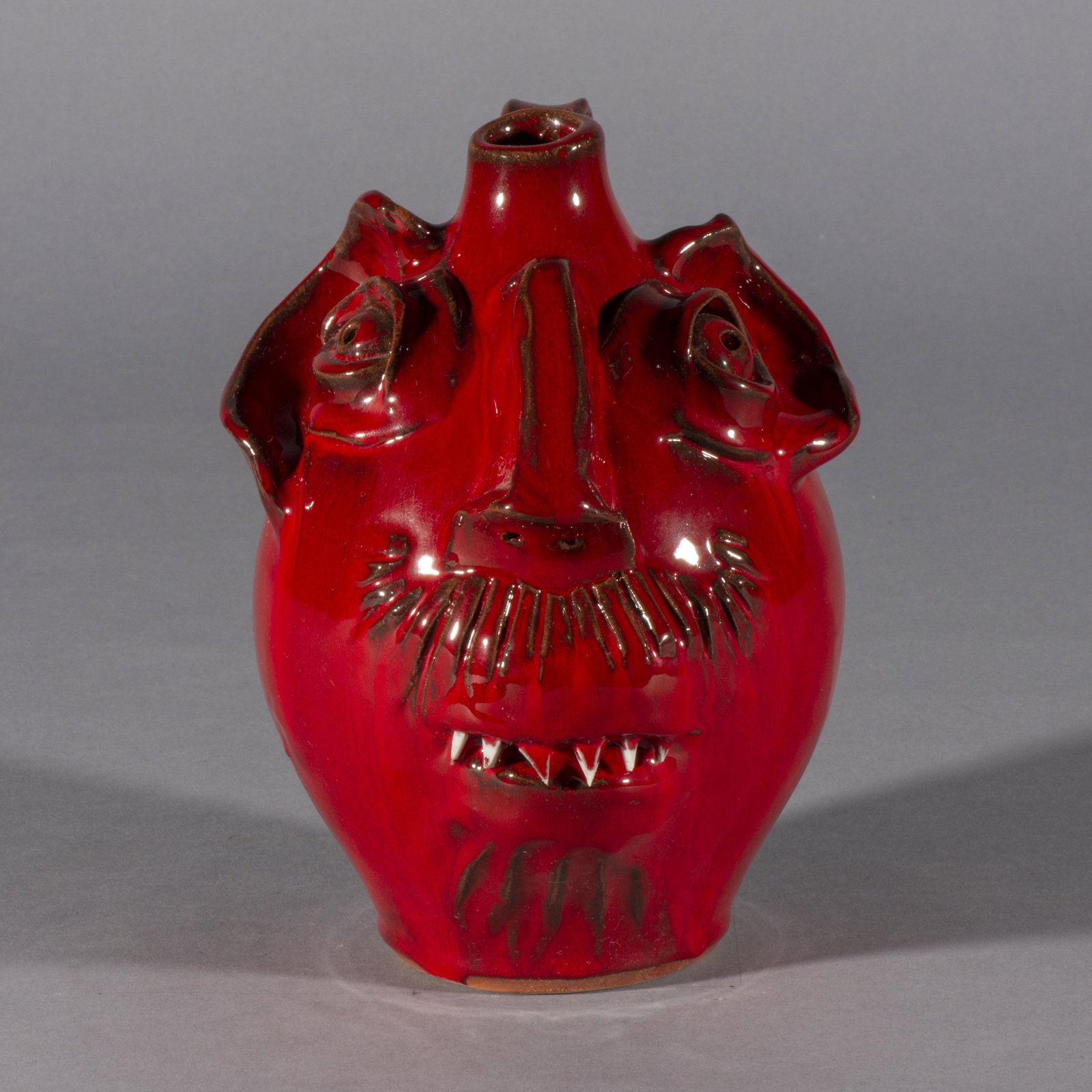 ML Owens Face Jug red: a fantastic red glazed face jug. This Red is very hard to make. ML Owens was known for his red glaze. Signed on bottom ML OWENS. Sharp china teeth. Height is 8.5"