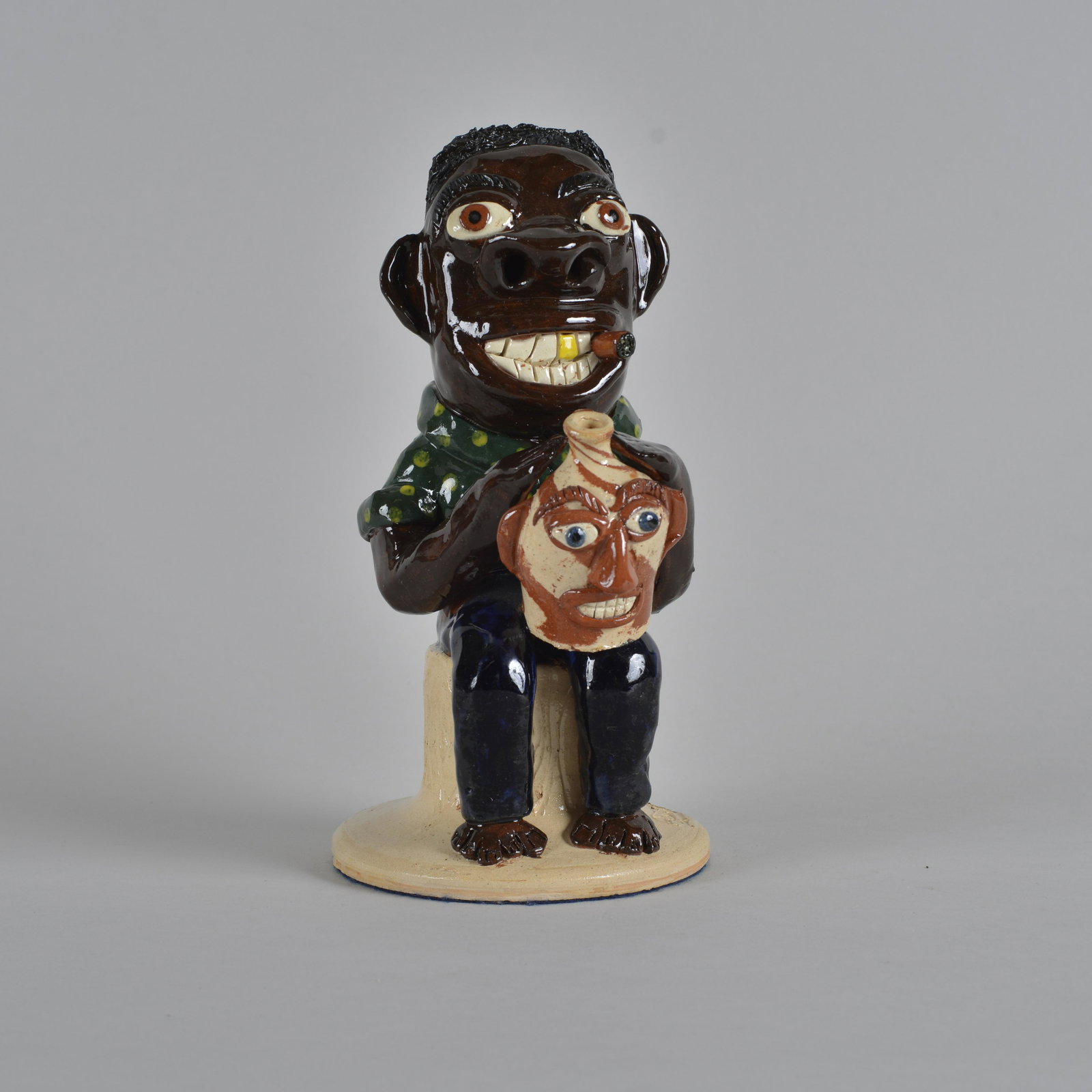 Albert Hodge Figural Statue: a great piece of folk pottery by Albert Hodge. Stamped on top side of base Albert Hodge, cigar in mouth gold tooth holding a great miniature face jug. A fantastic piece of ART! Height 9.75"