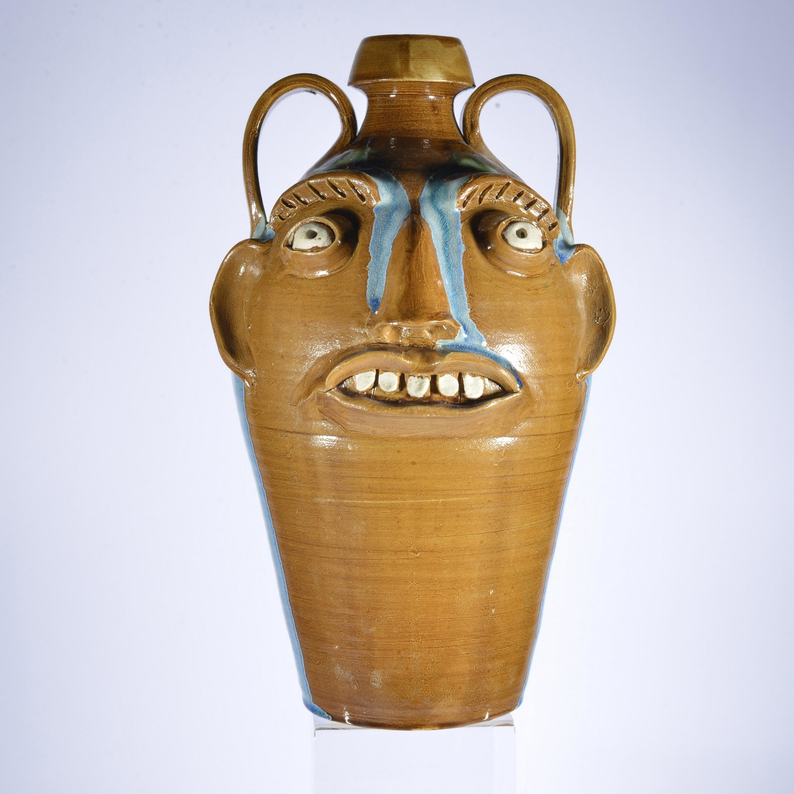 RANDY TOBIAS TALL GLASS DECORATED FACE JUG: Randy Tobias also really embraces symmetry in his pots. This is a great example he almost perfectly balances the glass he melts off the eyelids & handles. Stands 14" by 8". Signed Randy T on back & Ra