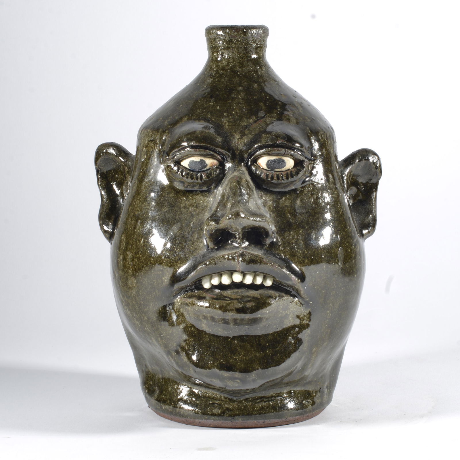 Lanier Meaders Face Jug: 10" alkaline glaze, clay eyes and teeth. Signed on bottom. Condition is excellent. 11"