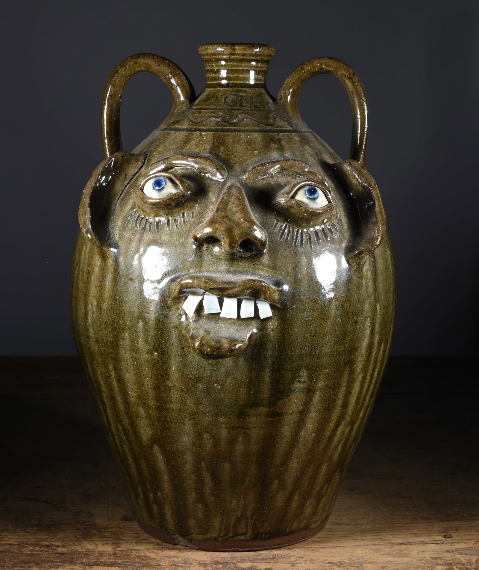 Charles Lisk Face Jug: 14" outstanding alkaline glaze, with a single row of broken china teeth, clay eyes with blue. Stamed under spout and on shoulder, double handled.