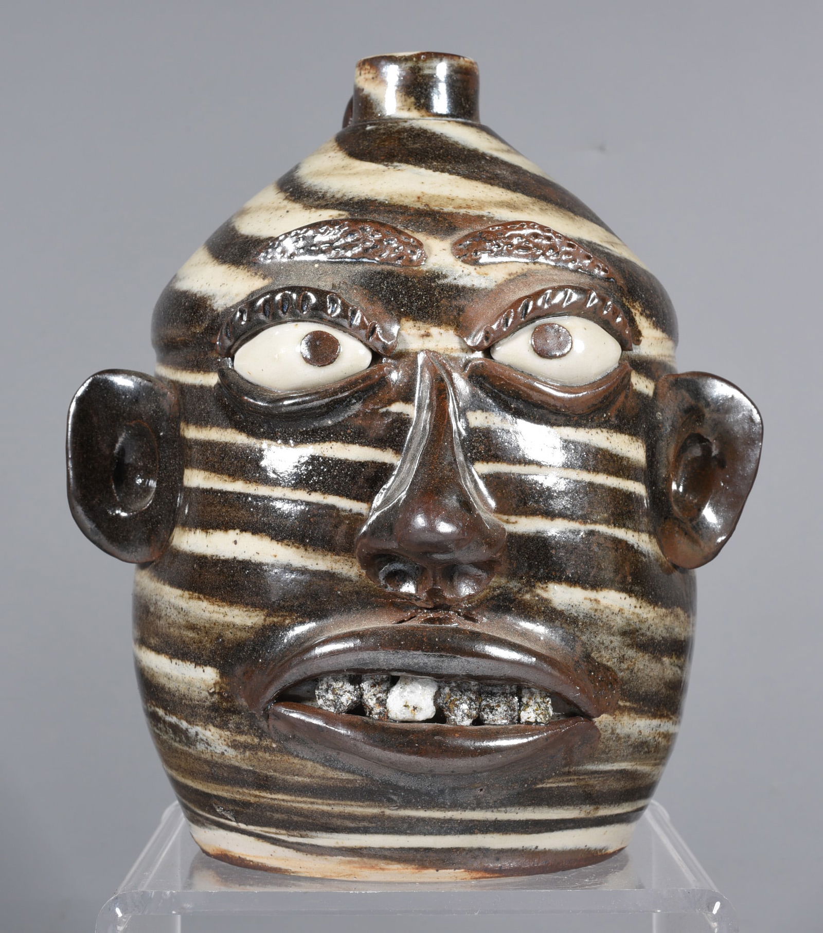 Wayne Hewell Rock Tooth Face Jug: 8'' swirl face jug with rock teeth, clay eyes. Signed on bottom. Seems to be in the style of Lanier Meaders.