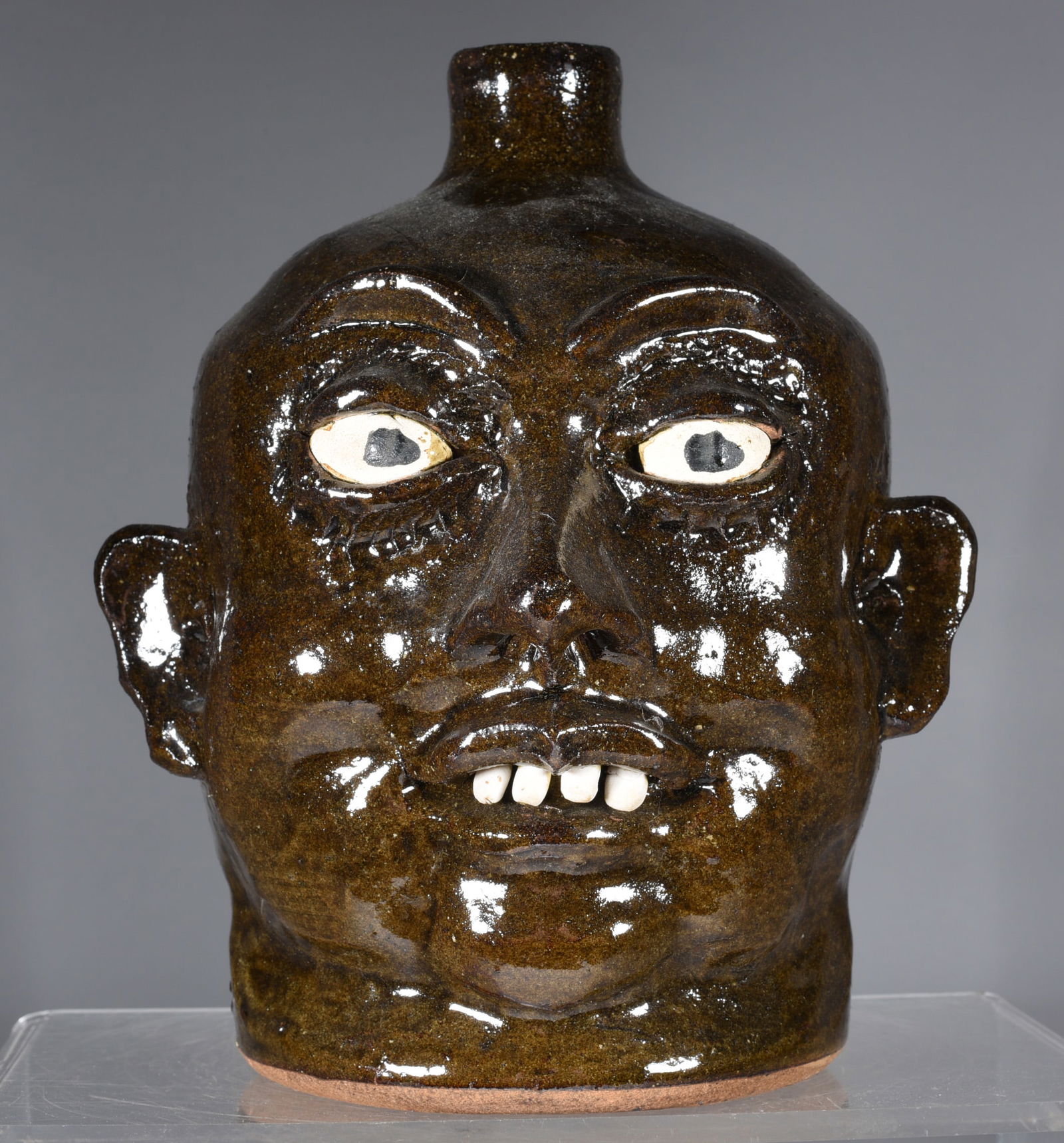Lanier Meaders Face Jug: 9" alkaline glaze face jug by Lanier Meaders. Clay eyes and clay teeth. Signed on bottom.