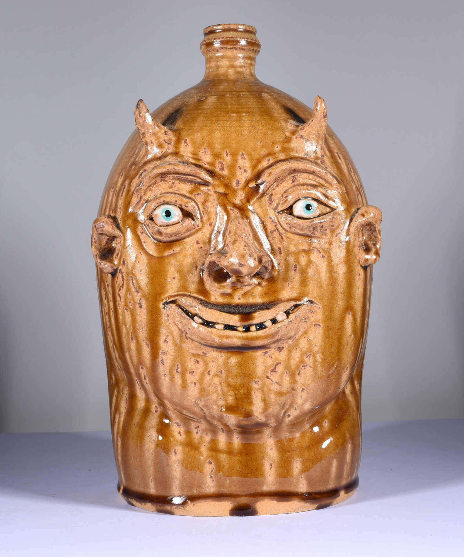 Marvin Bailey Devil Face Jug: 10.5" very nice lite brown glaze, a smiling devil face jug. Tiny clay teeth. Signed on bottom.