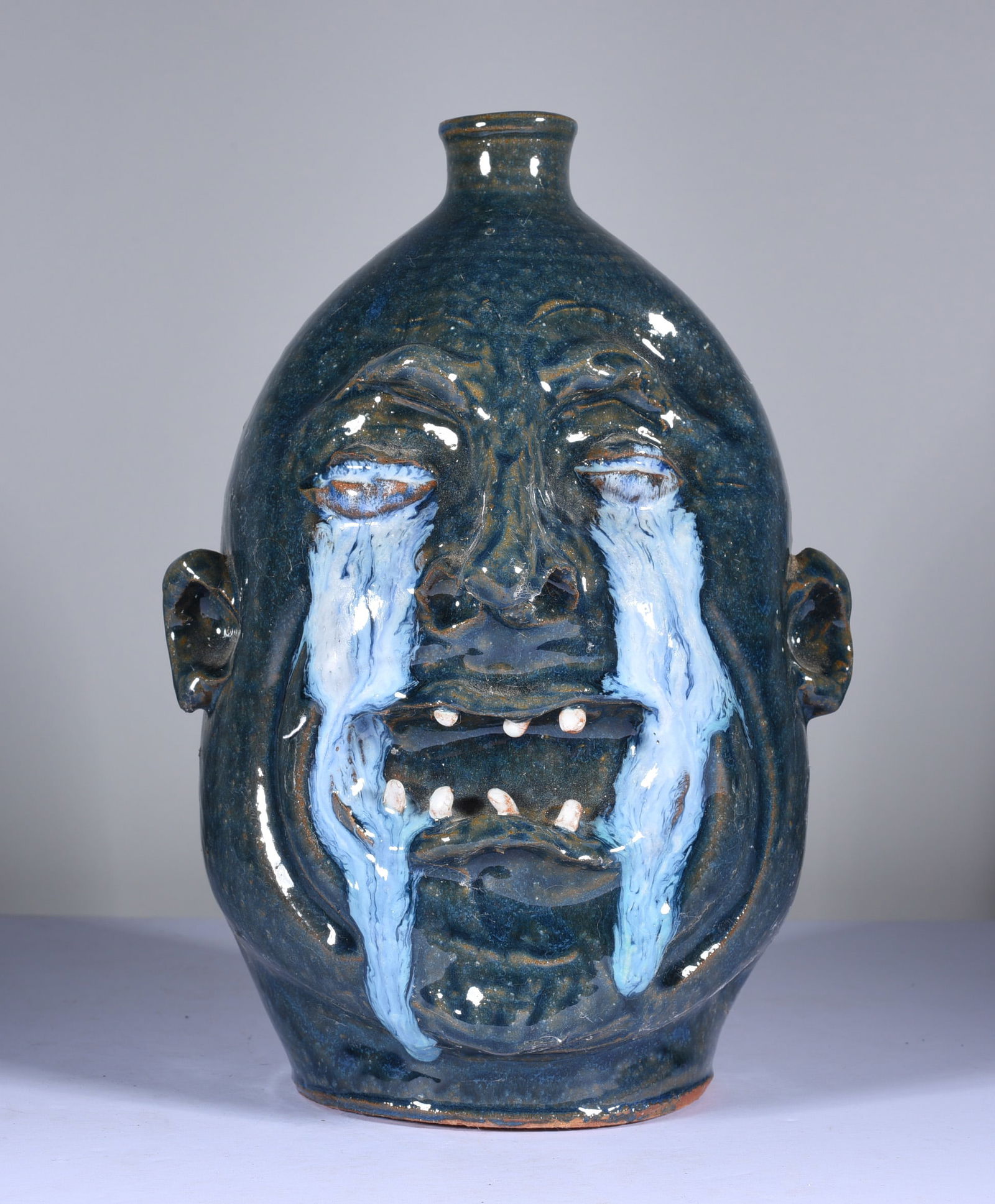 Marvin Bailey Crying Eye Face Jug: 9" outstanding crying eye face jug by Marvin Bailey. Very nice blue green glaze with a double row of clay teeth. Signed on bottom. Mint condition.