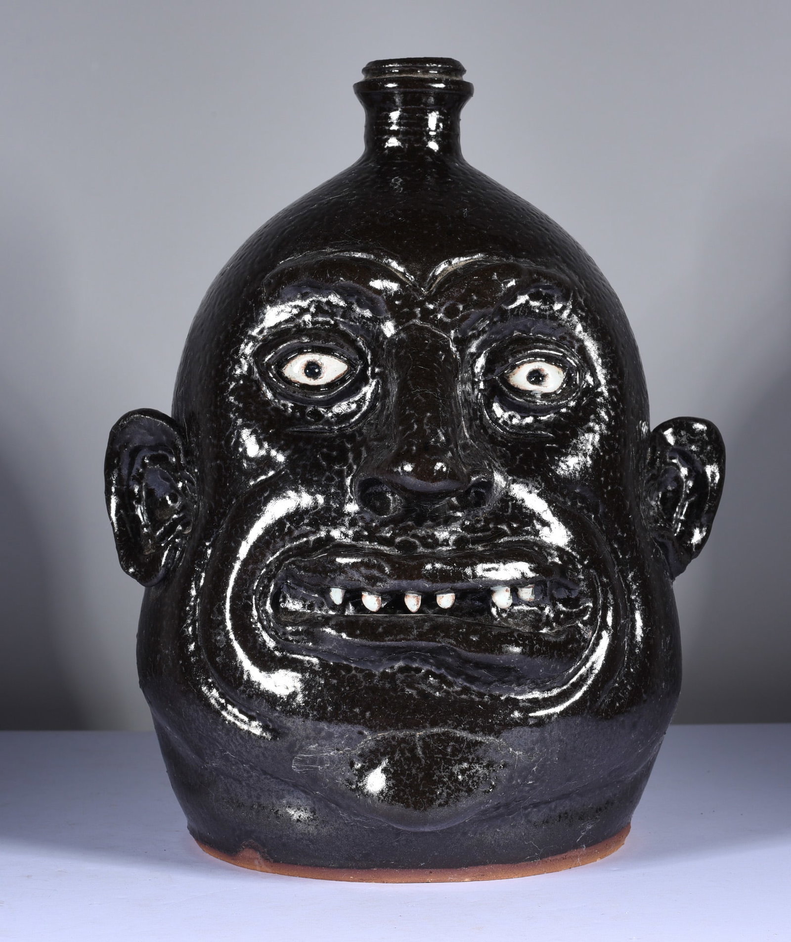 Marvin Bailey Face Jug: 10.5" a rare dark textured glaze with a single row of clay teeth. Signed on bottom. A very nice round face jug with oner inhanced facial features. Mint condition.