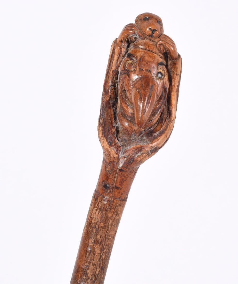 Folk Art Carved Cane Puppy Dog on Head of Man: Interesting carved cane with puppy dog above a fellows head or a large nose figure with the hands holding the dog. Full body dog on verso.