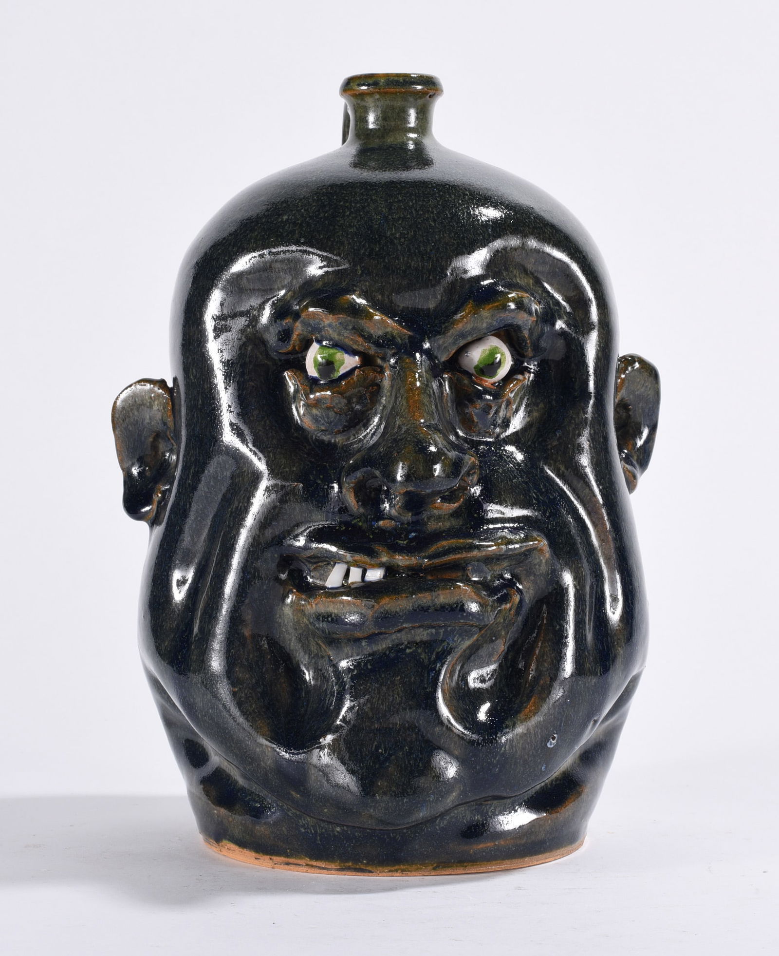 Marvin Bailey Grumpy Face Jug: a dark glazed face jug with china plate teeth and clay eyes. Signed on bottom.