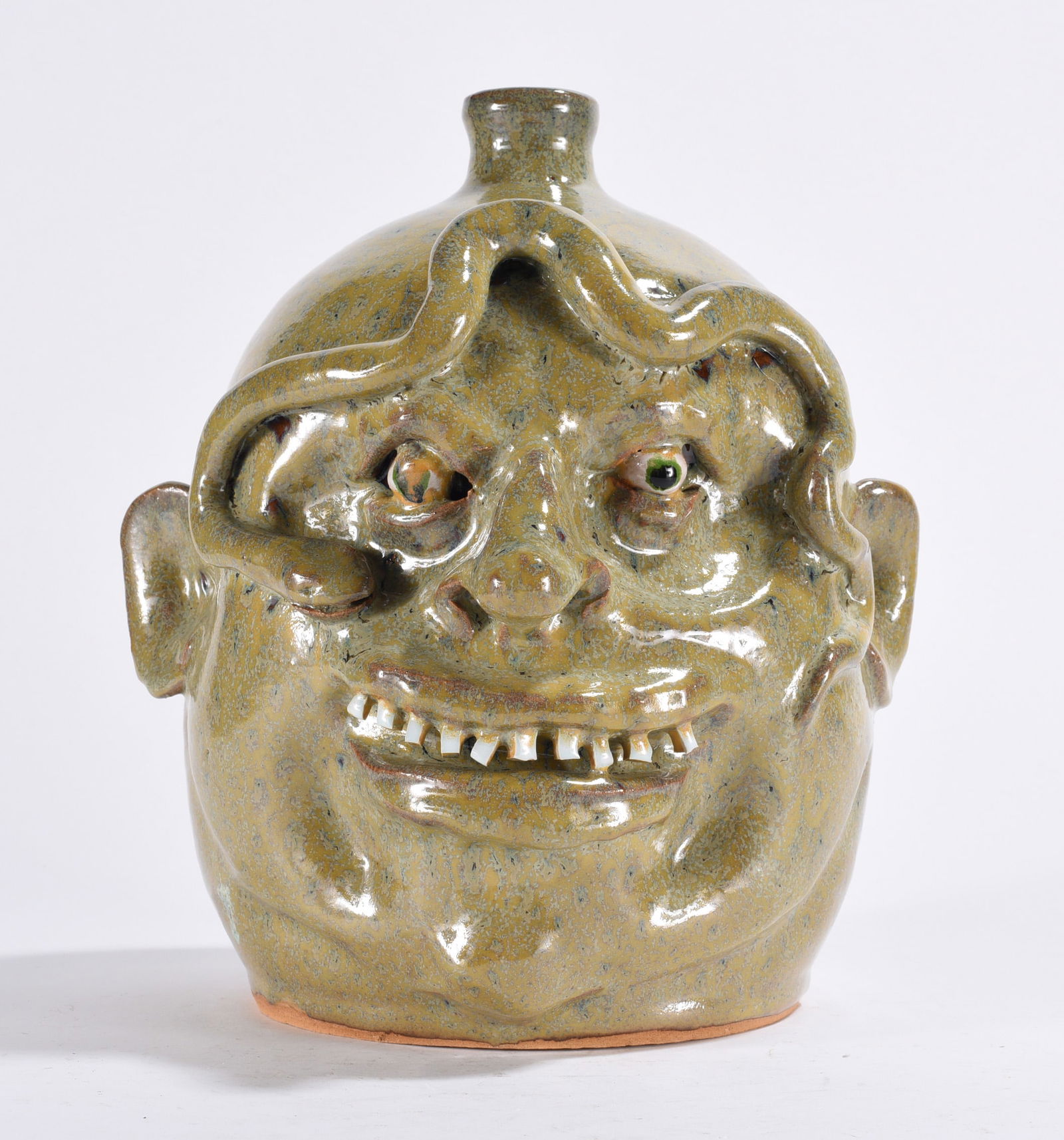 Marvin Bailey Face Jug w/ Snake: a lite glaze face jug with china plate teeth and clay eyes with a snake crawling on his forehead. Signed on bottom.