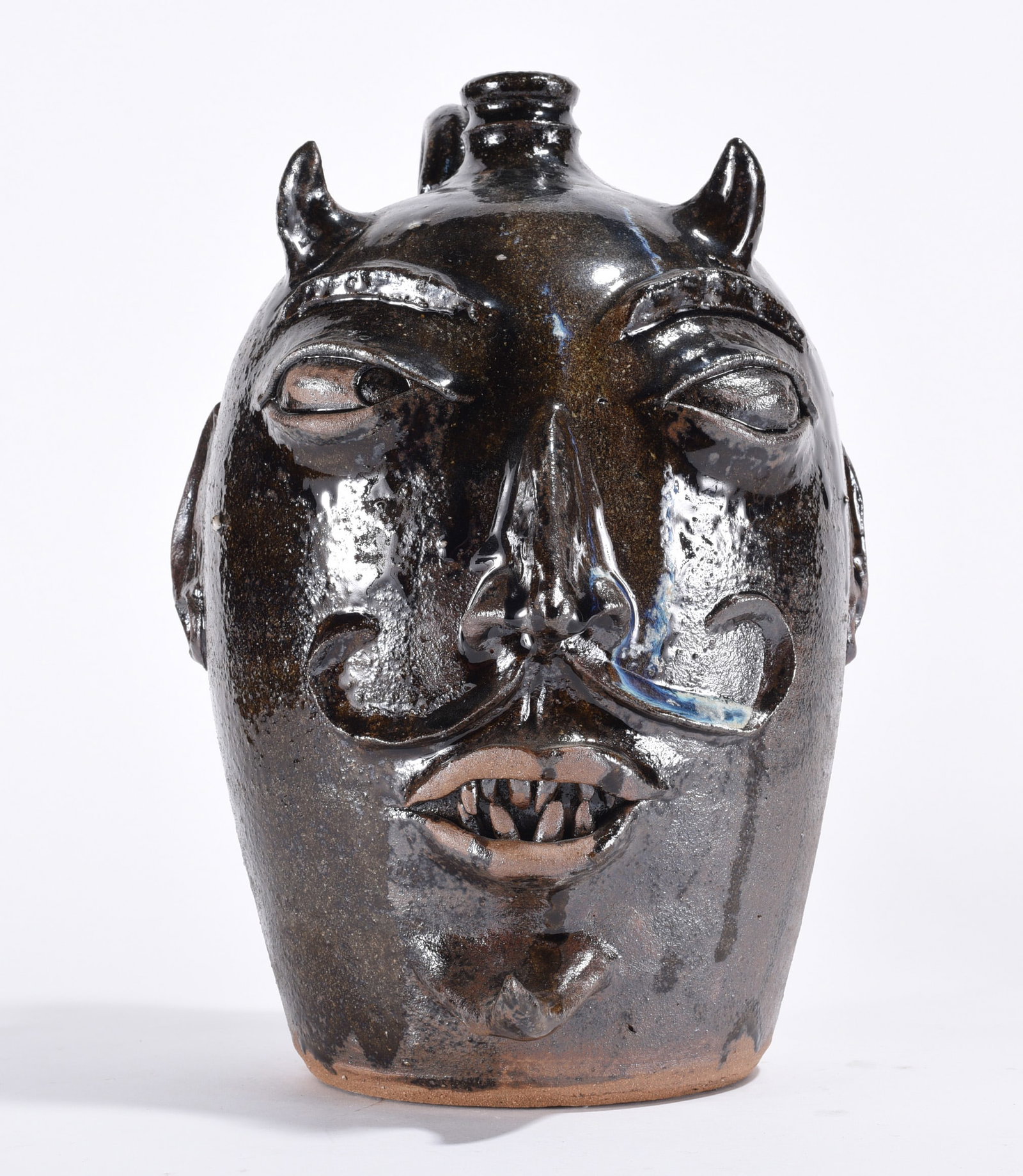 Michele Bayne Devil Face Jug: 10.5" - pottery face jug by Michele Bayne with clay eyes and clay teeth. A dark glaze with a blue run down the back. Signed on the back side.
