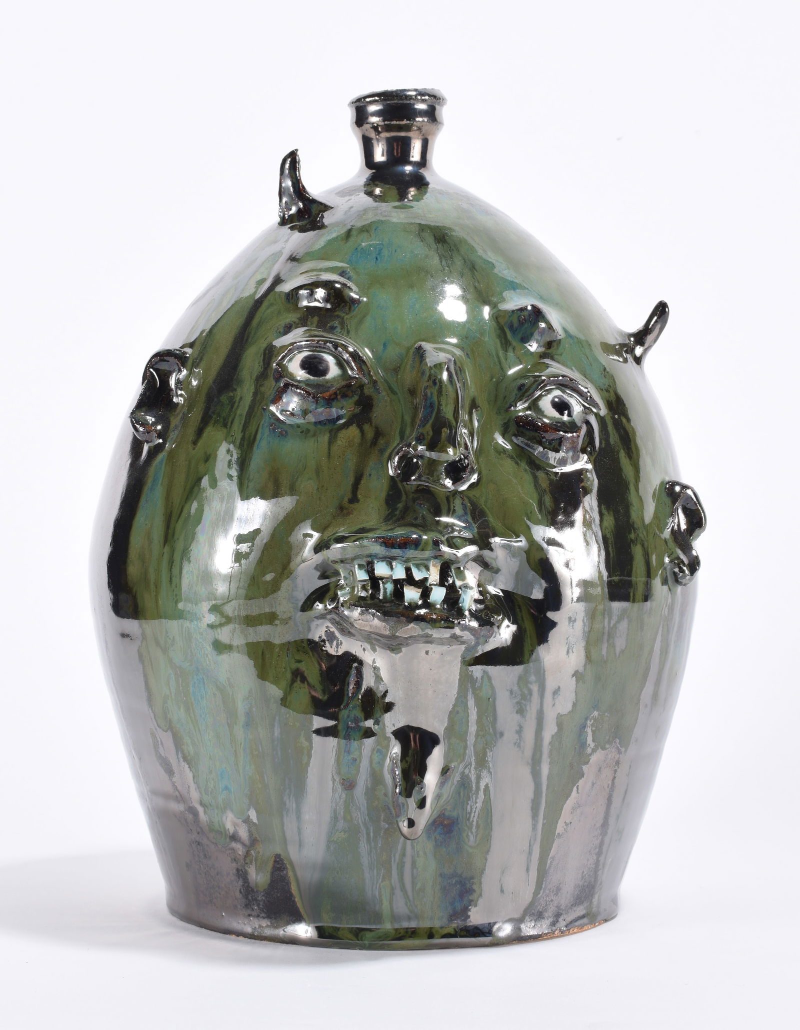 Marvin Bailey Face Jug: 11" - face jug in a mirror like glaze with green highlights. Two rows of small china plate teeth. Crooked small devil horns at the top. Clay eyes. Signed on bottom.