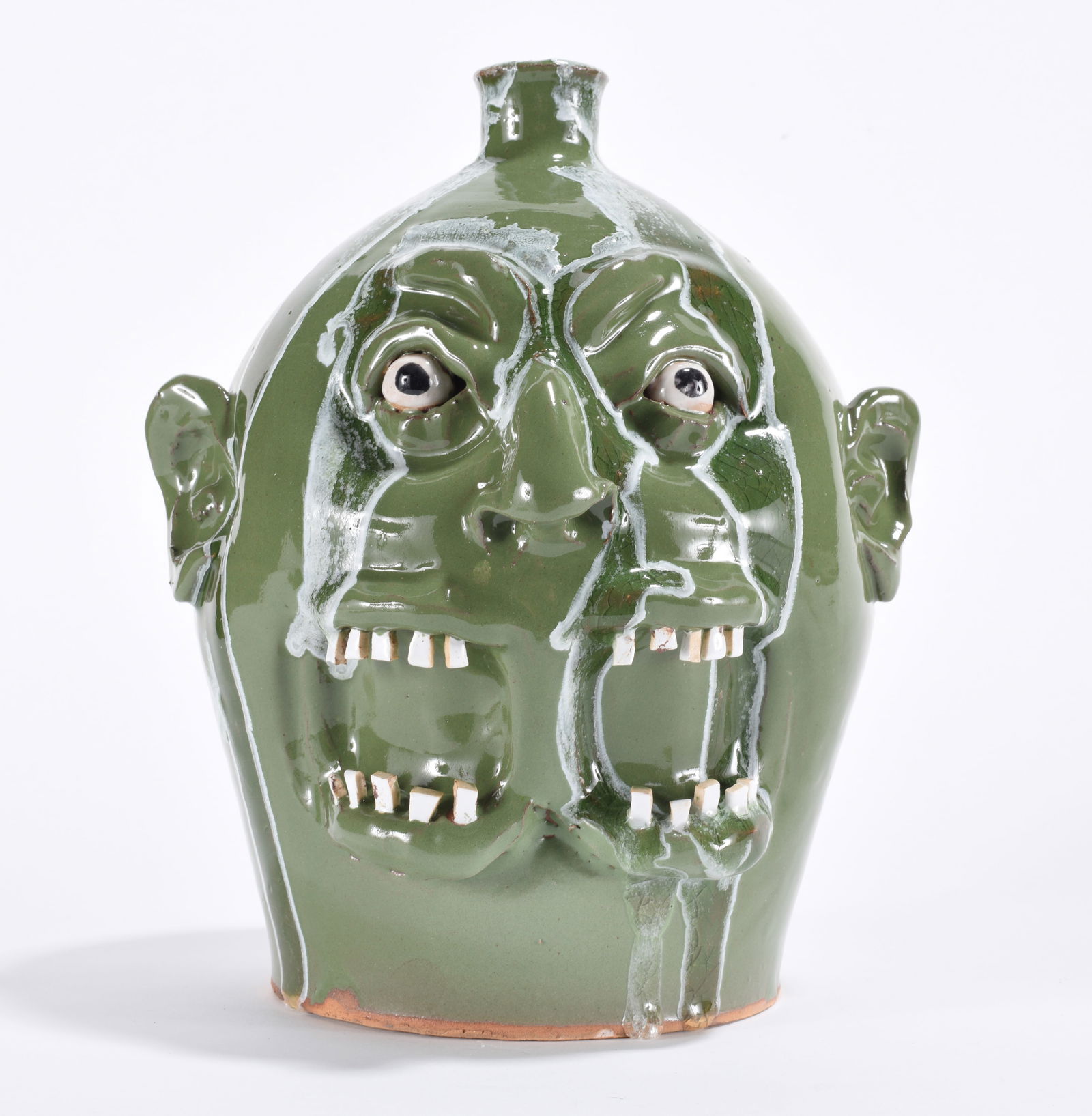 Marvin Bailey Siamese Twin Face Jug: 10" - one body, 2 eyes, 2 mouths, a green base glaze with a dark green and white run. Two sets of china plate teeth. Clay eyes. Signed on bottom.