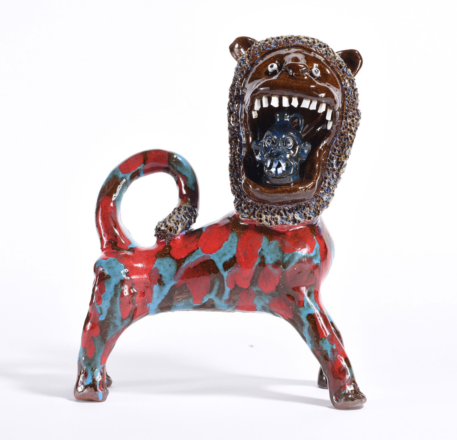 Marvin Bailey Lion Figural: pottery lion by Marvin Bailey with china plate teeth. Eating a miniature face jug. Signed.